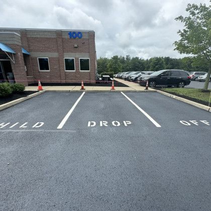 Child drop off zone with marked spaces in front of a brick building; parked cars in background.