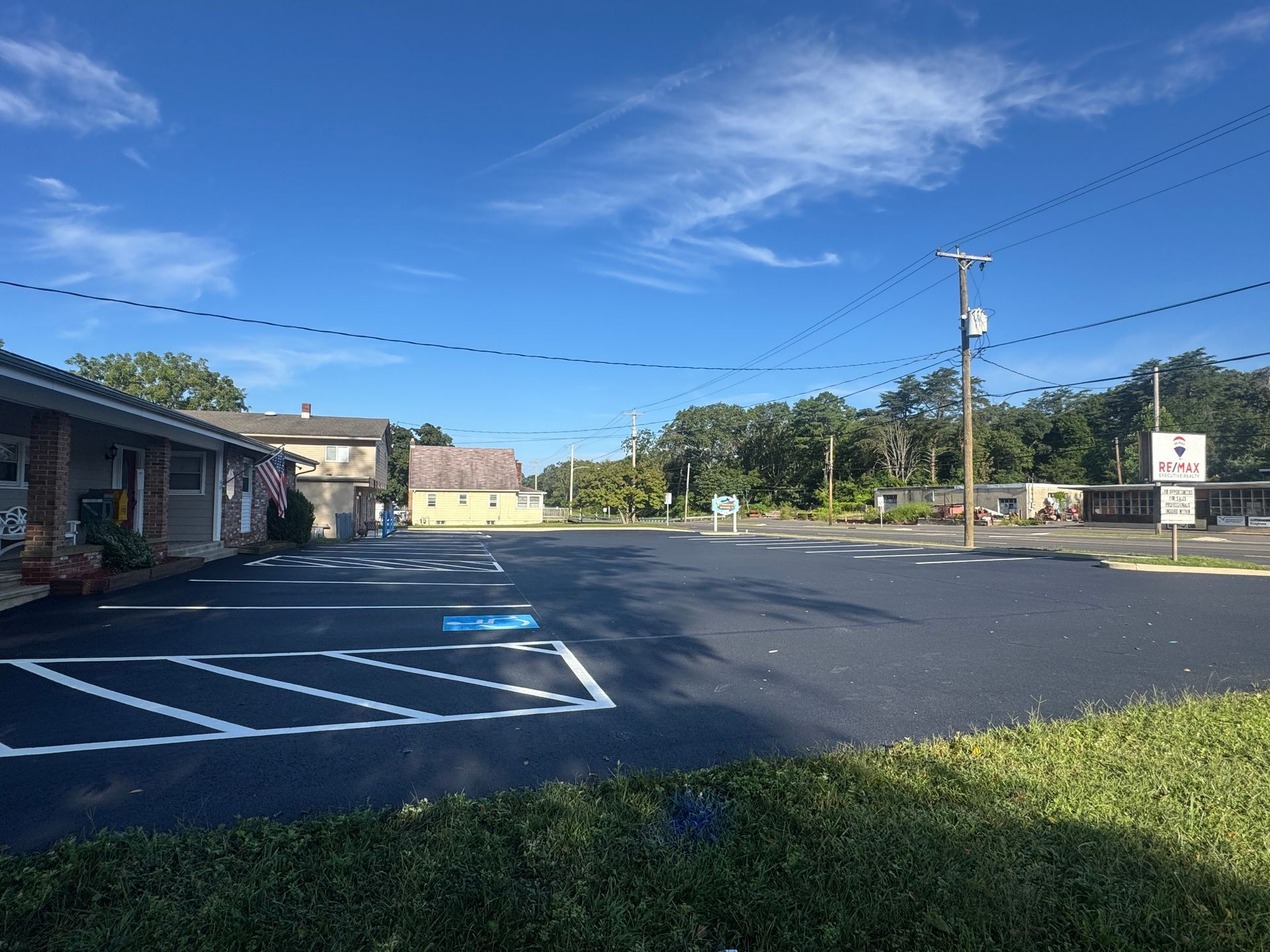 Paved parking lot with handicap space, low buildings, blue sky.