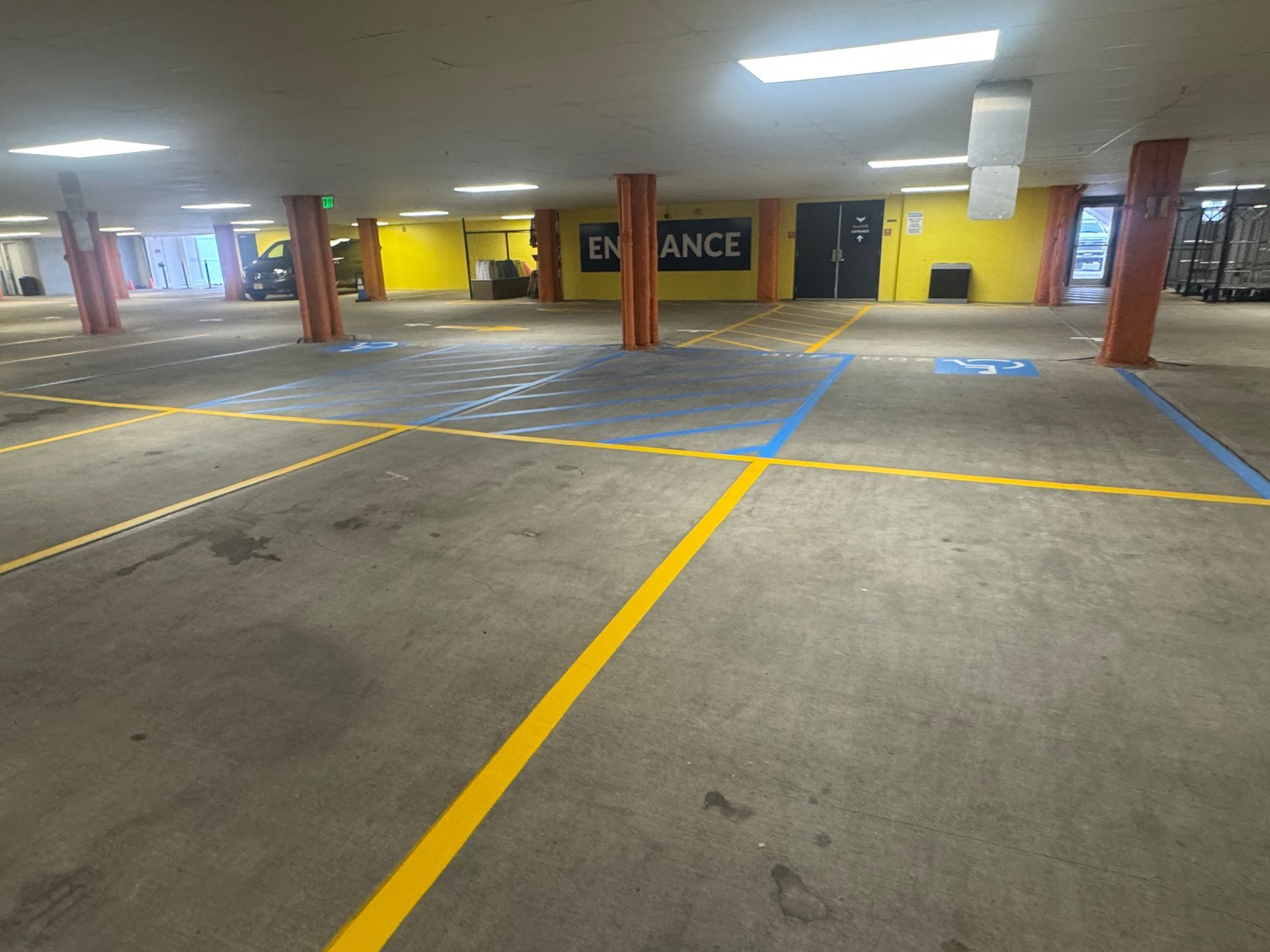 An empty parking garage with yellow and blue lines, orange support columns, and an 