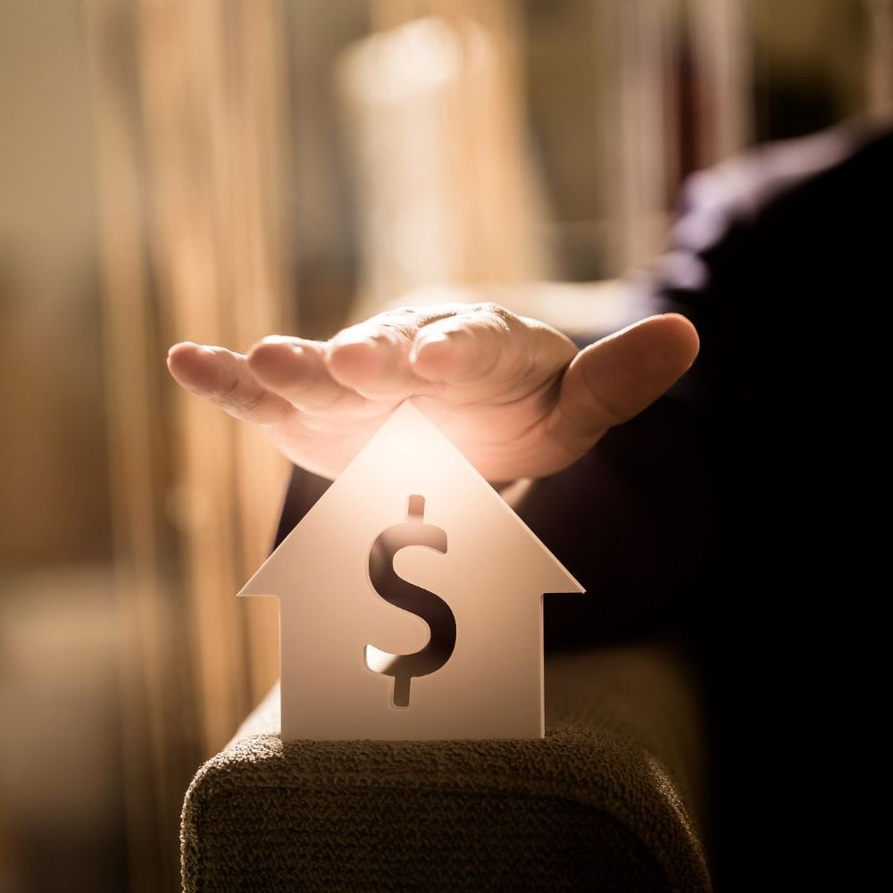 A hand is holding a small house with a dollar sign on it  for Fraser Corporate Finance.