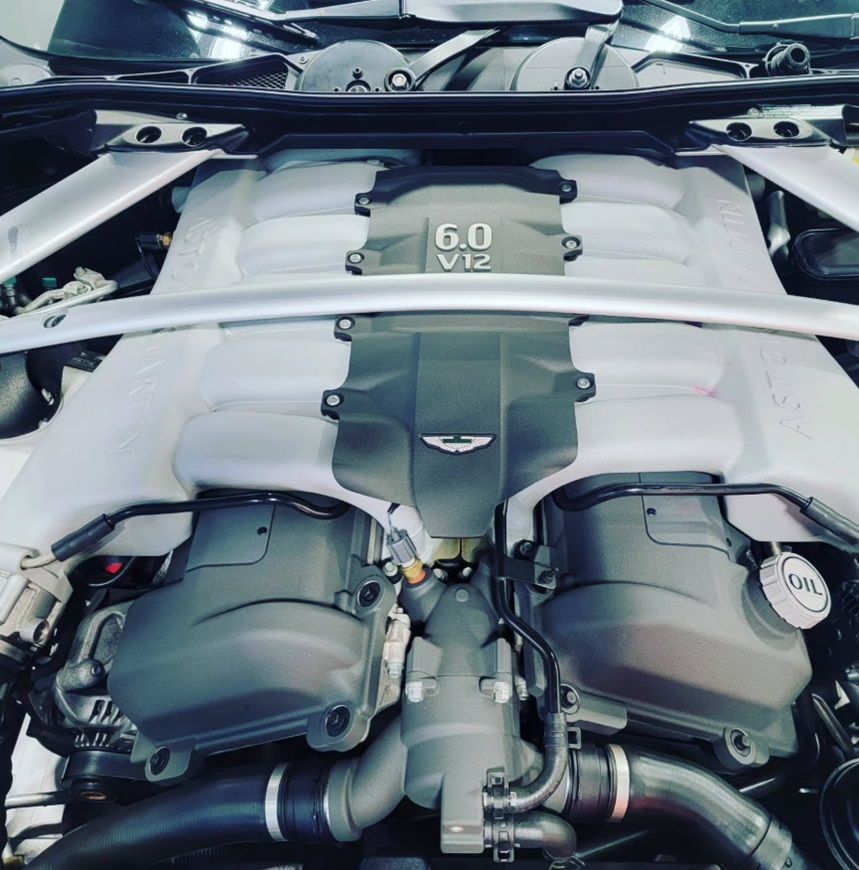 The exposed engine of an Aston Martin in for repairs at our shop