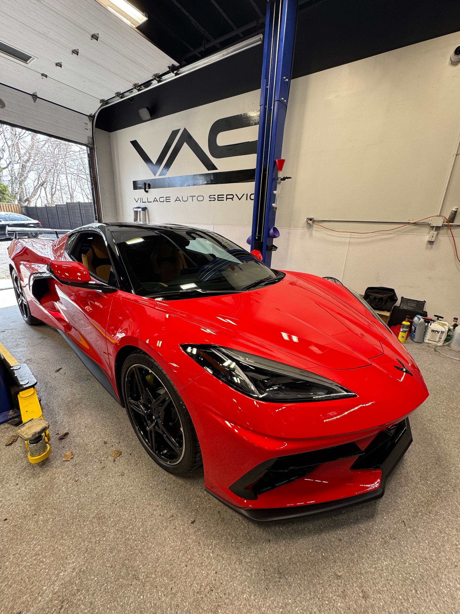 Red sports car in a garage with a VAC sign on the wall