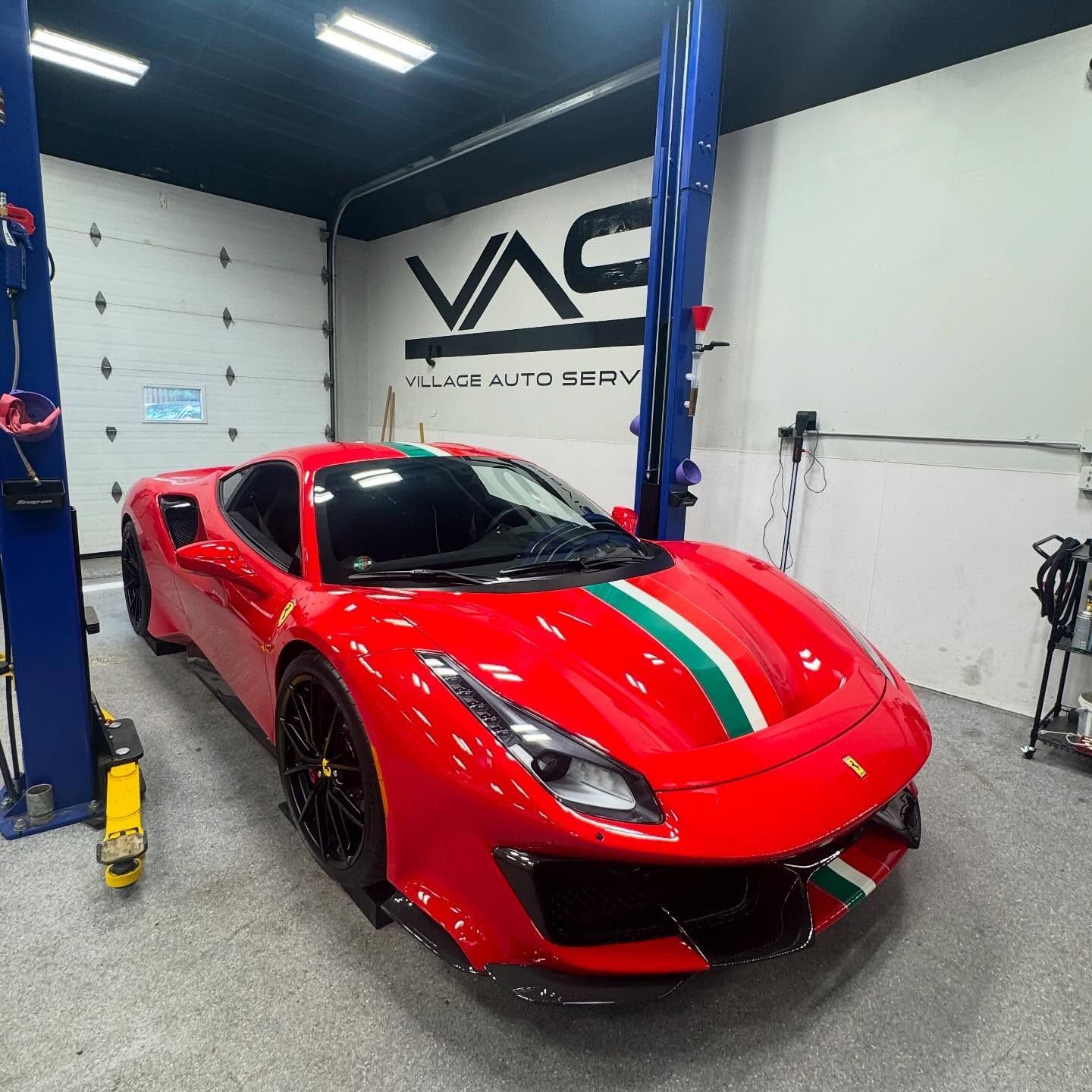 Red Ferrari parked inside Village Auto Service for auto maintenance.