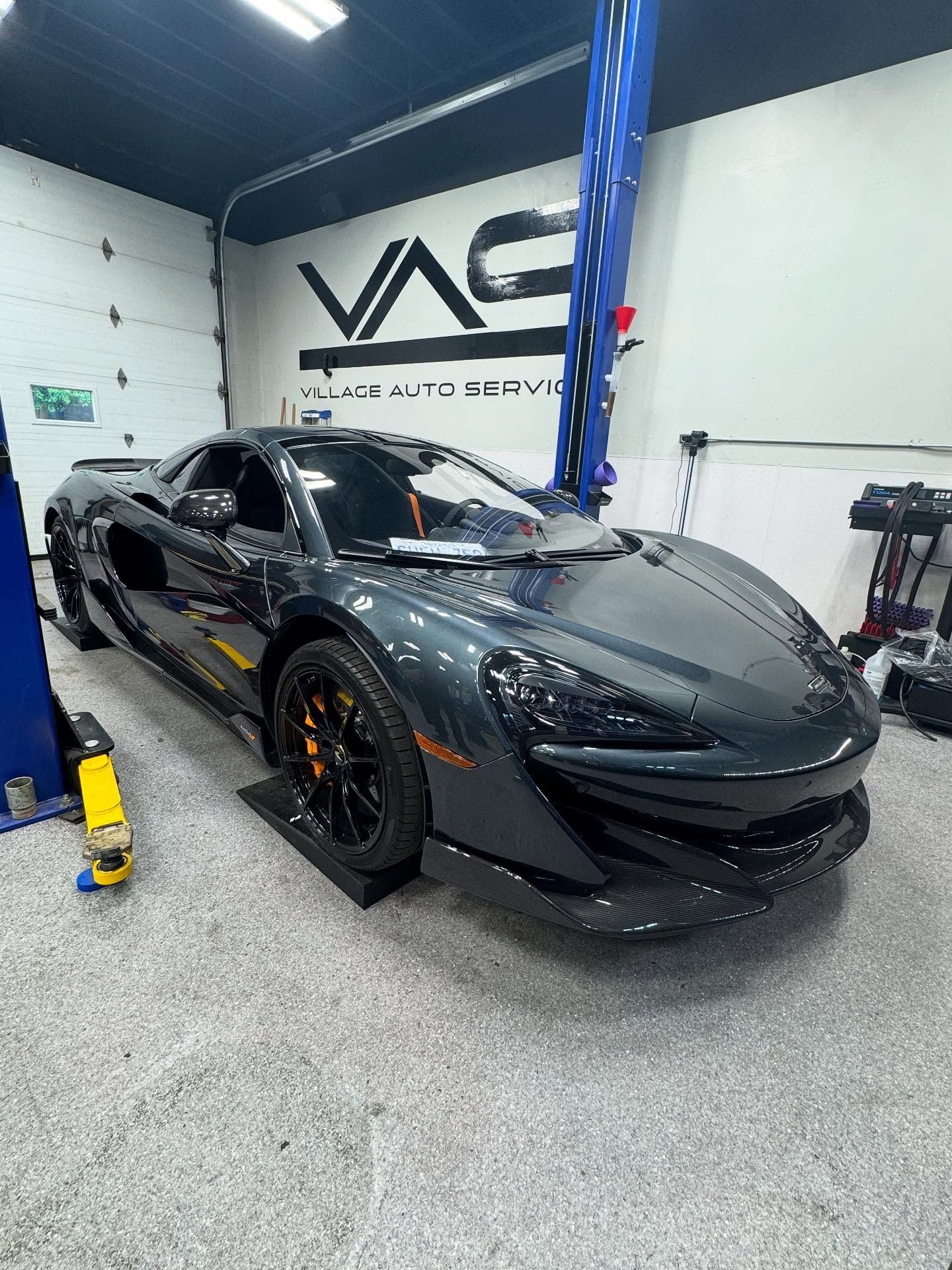 Black McLaren parked inside Village Auto Service for car maintenance.