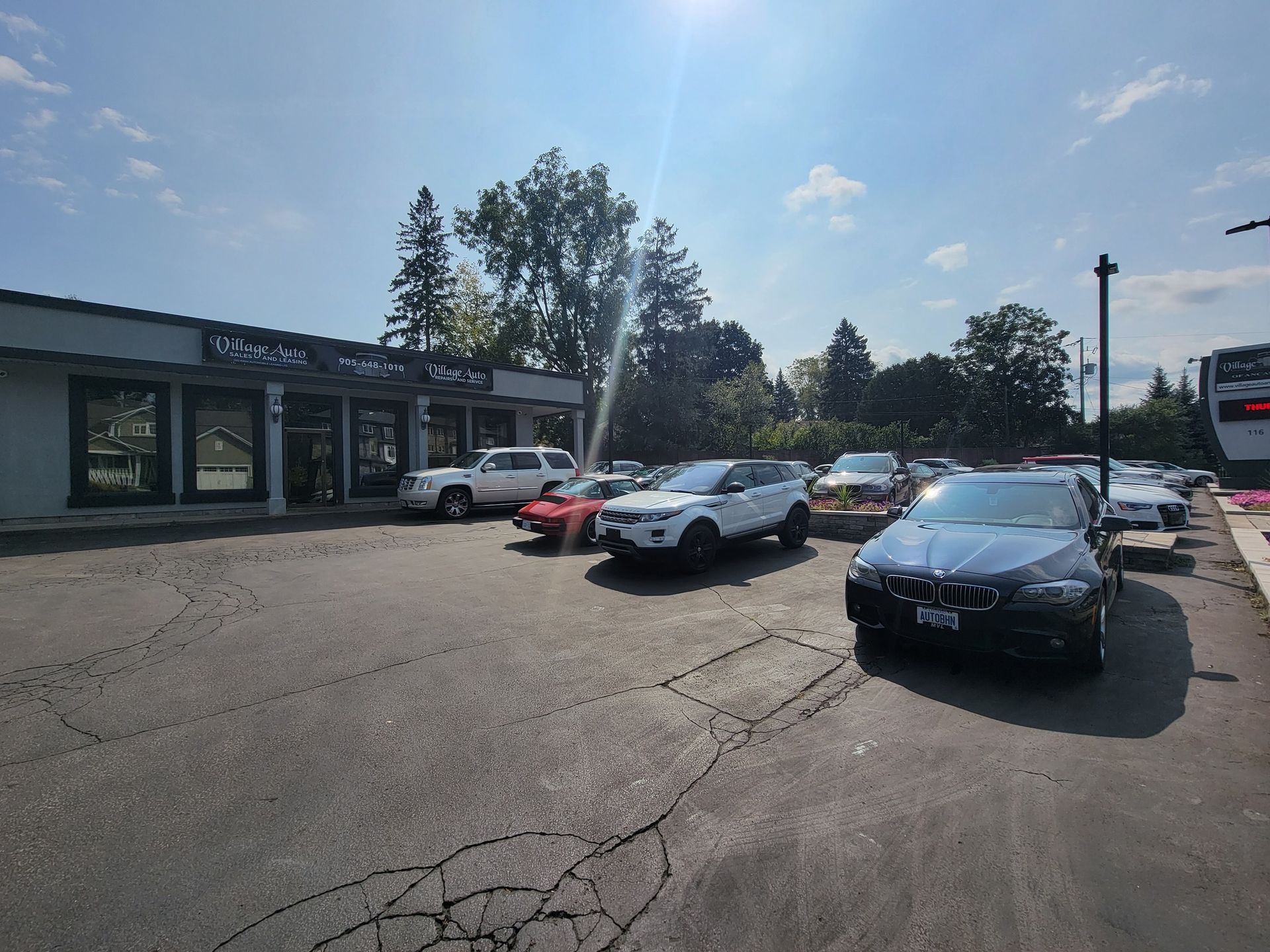 Parking lot with several cars beside a low storefront on a sunny day