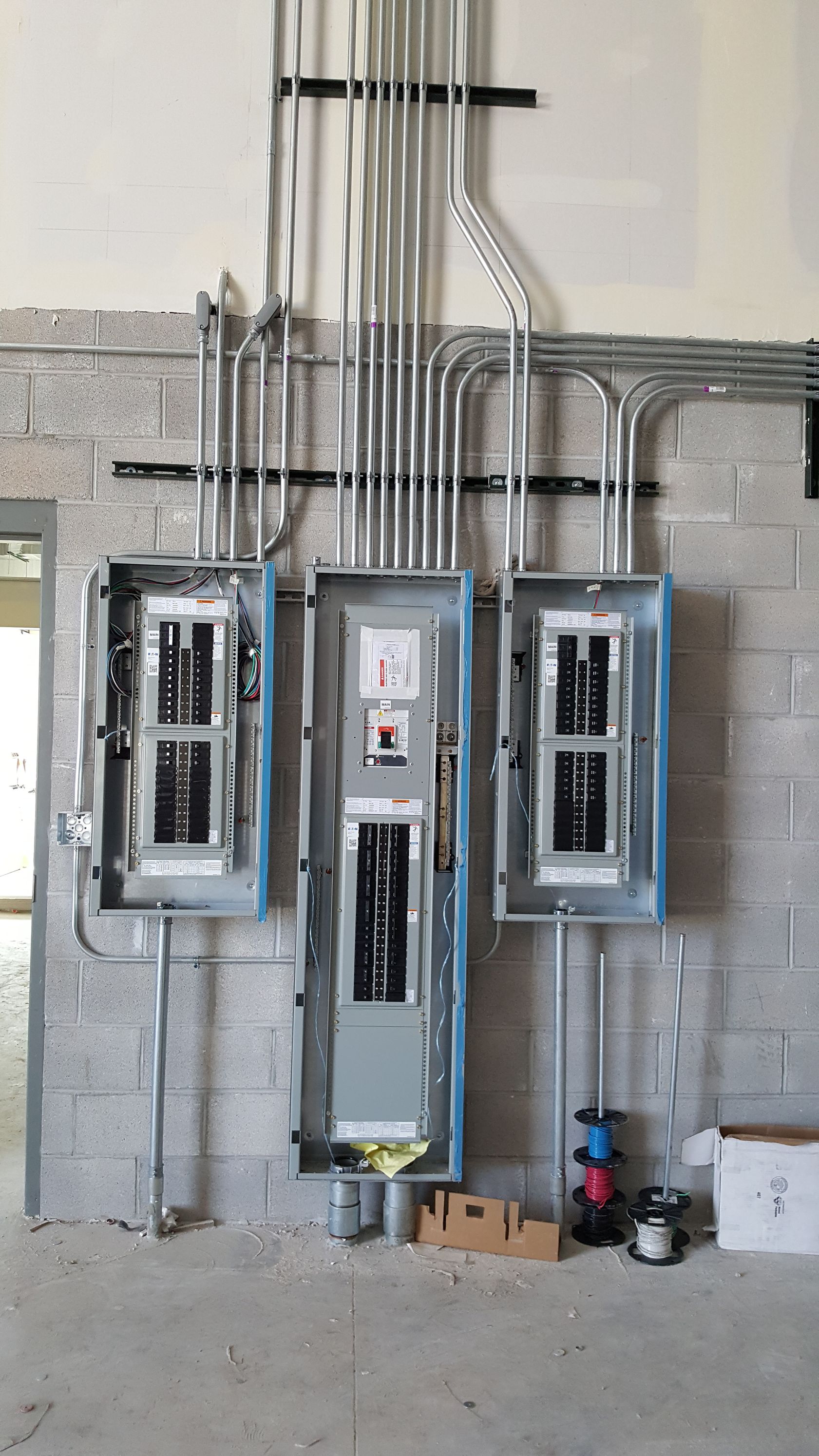 Two electrical panels are hanging on a brick wall.