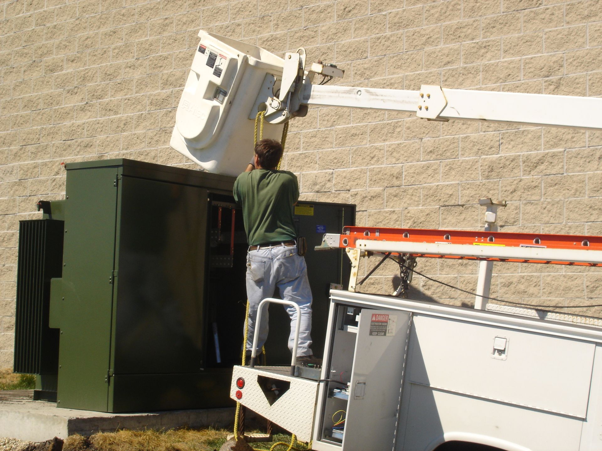 A man is standing on a ladder next to a crane.