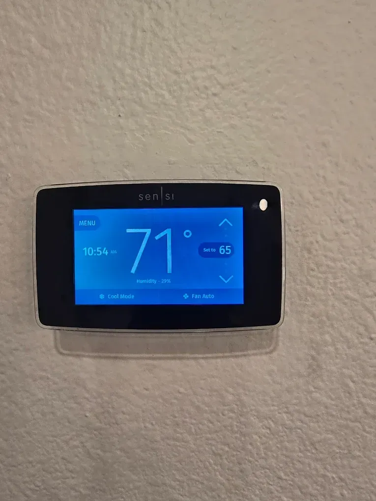 Blue wall-mounted thermostat showing 71° on a beige wall