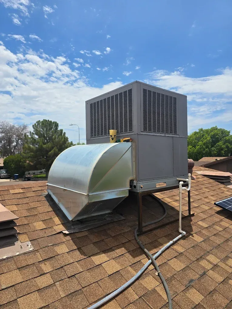 Rooftop HVAC unit with a large silver ventilation duct under a blue sky