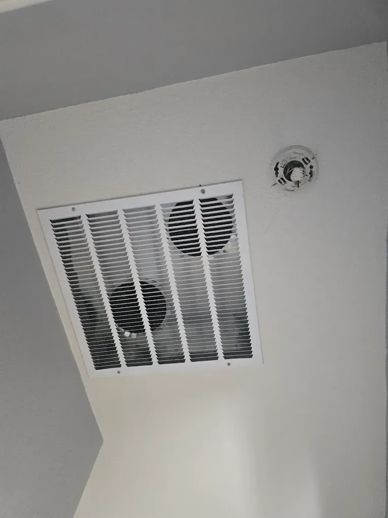 Ceiling vent and smoke detector on a white ceiling