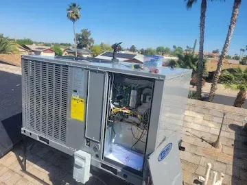 Outdoor HVAC unit with an open service panel beside a brick wall under palm trees