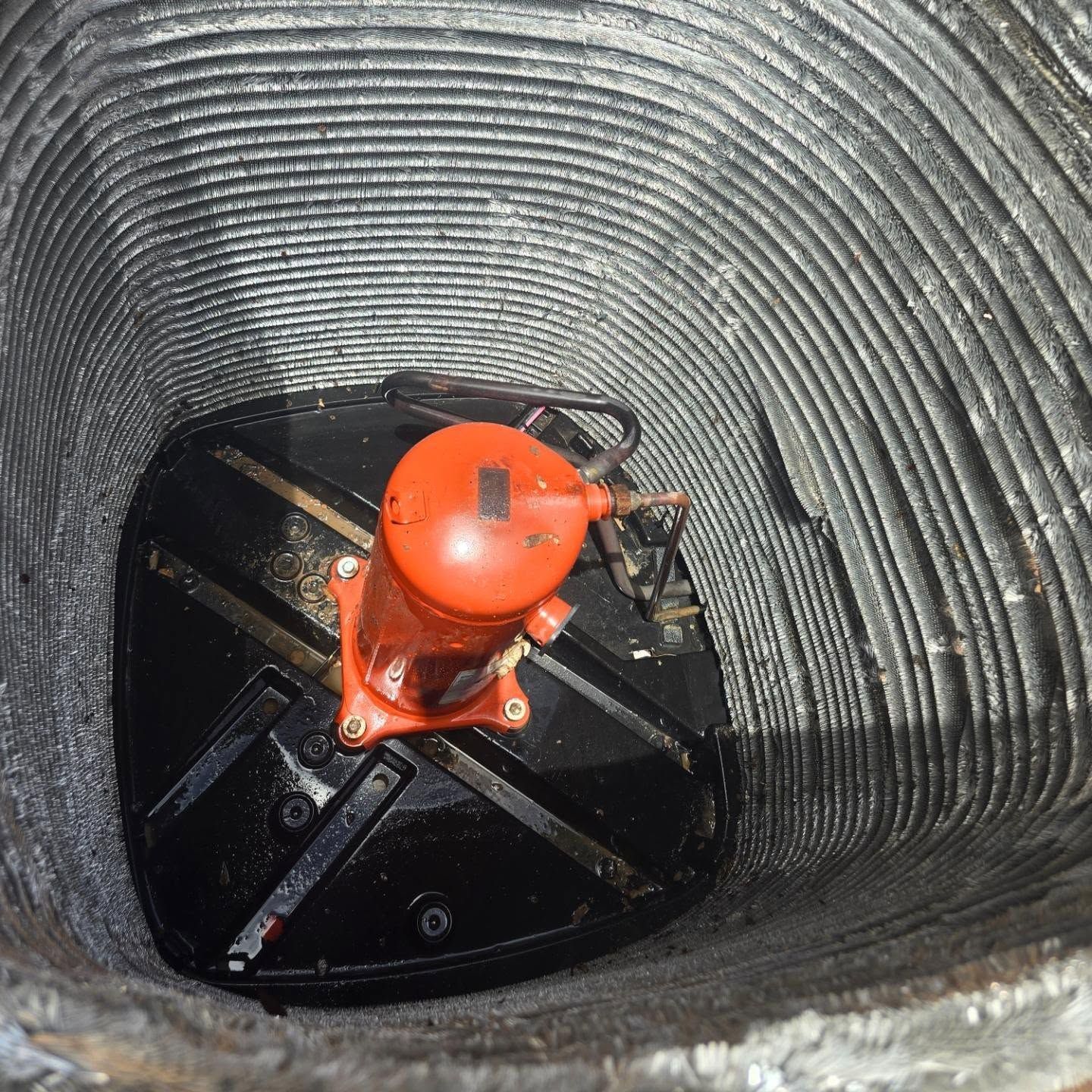 Orange valve mechanism inside a corrugated pipe or tunnel opening.