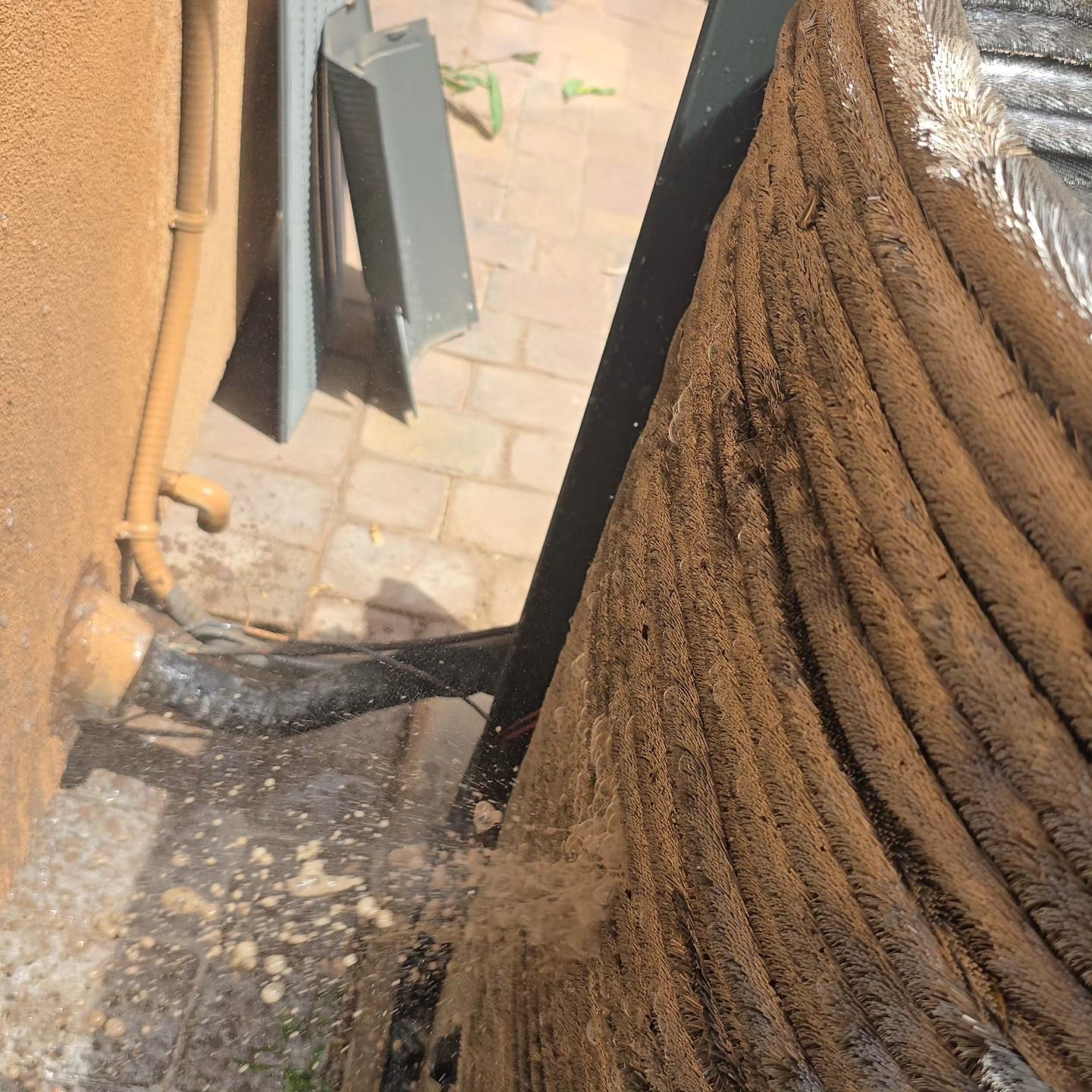 Charred debris and smoke damage beside a doorway on a tiled patio area