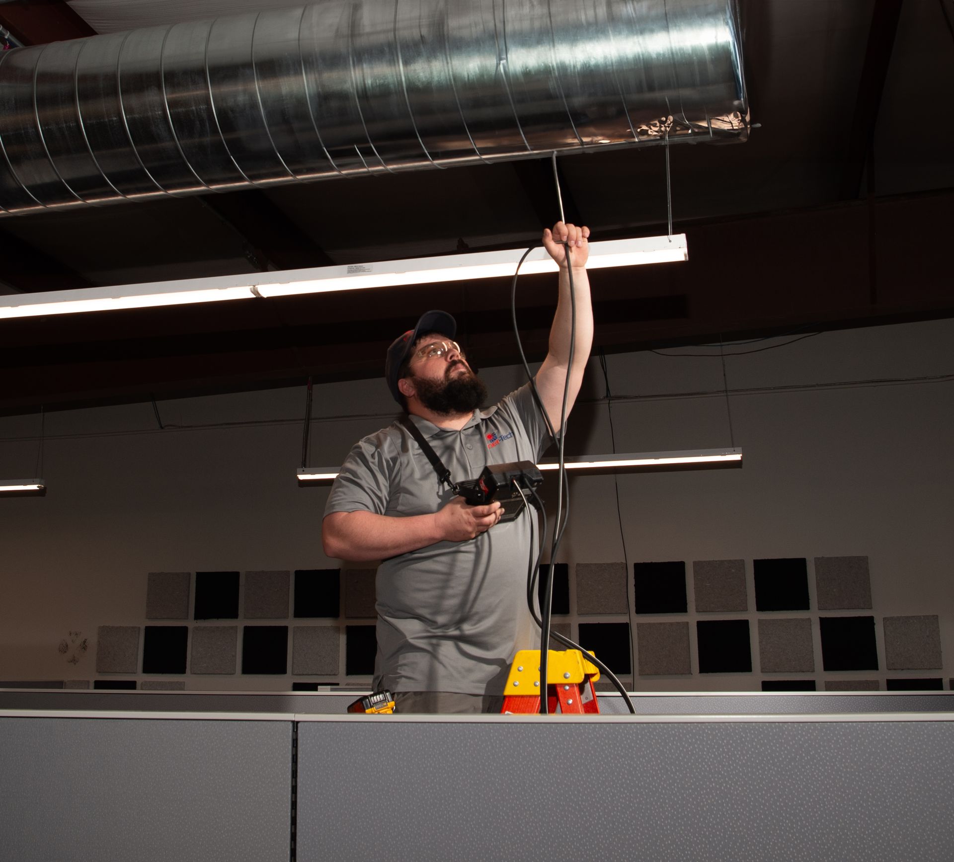 A man with a beard is working on a ceiling fan.
