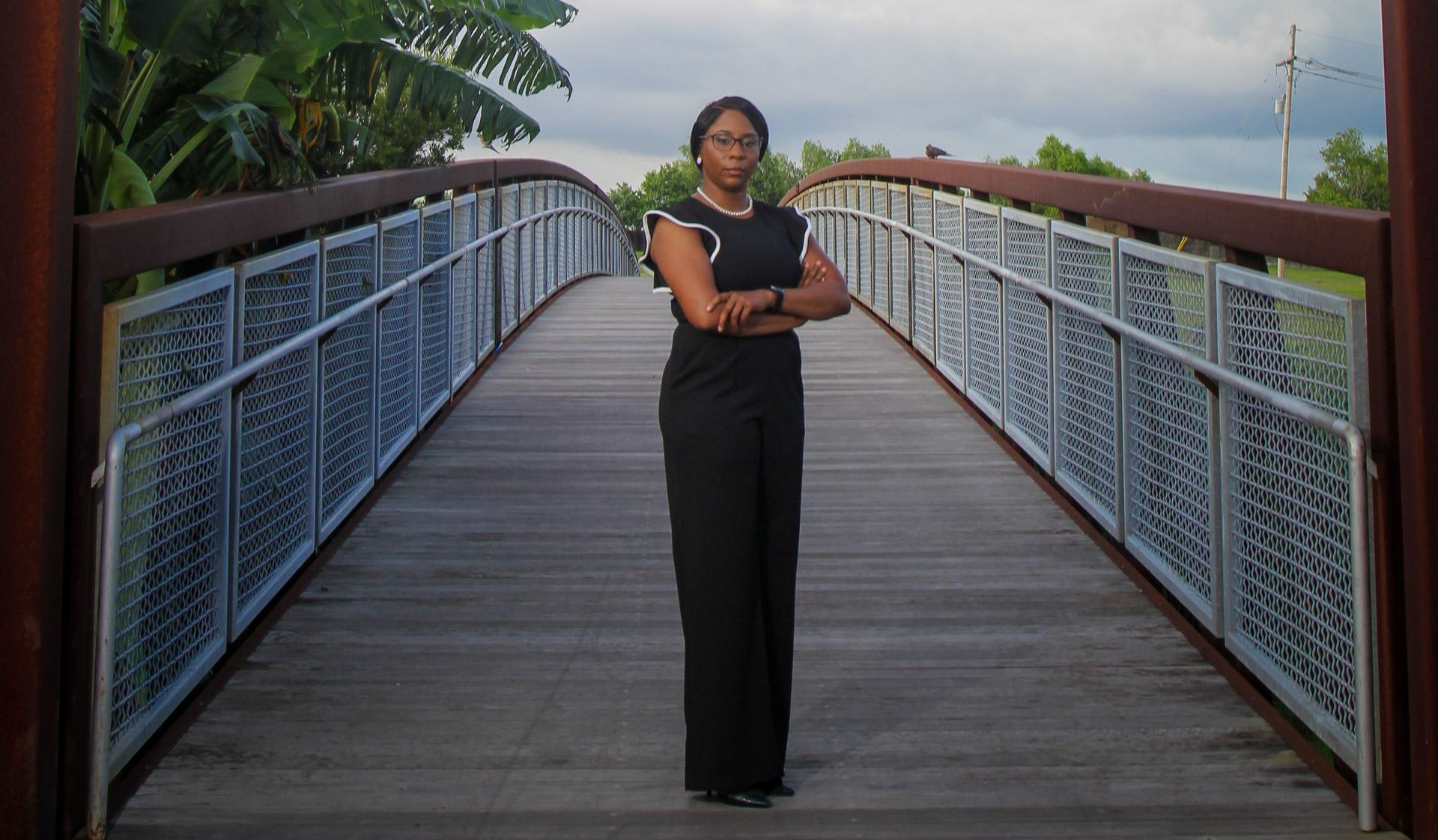 A woman is standing on a bridge with her arms crossed