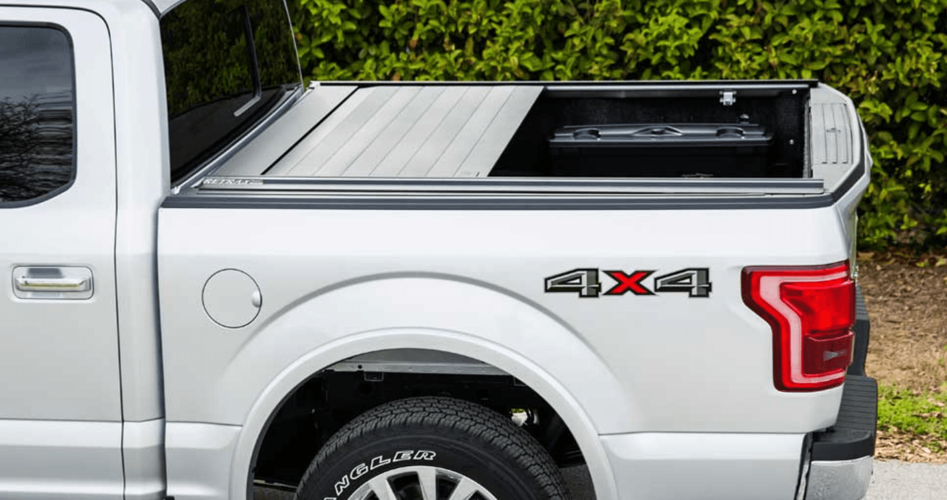 A silver truck with a black bed cover is parked on the side of the road.