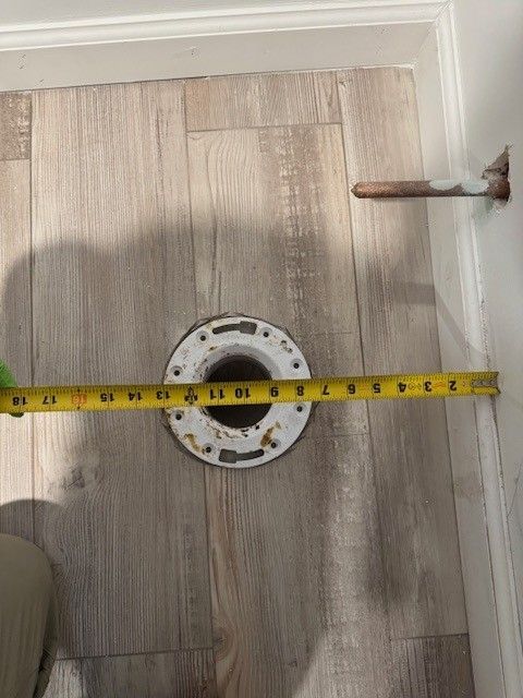 Bathroom floor with a shower drain and a yellow measuring tape across it