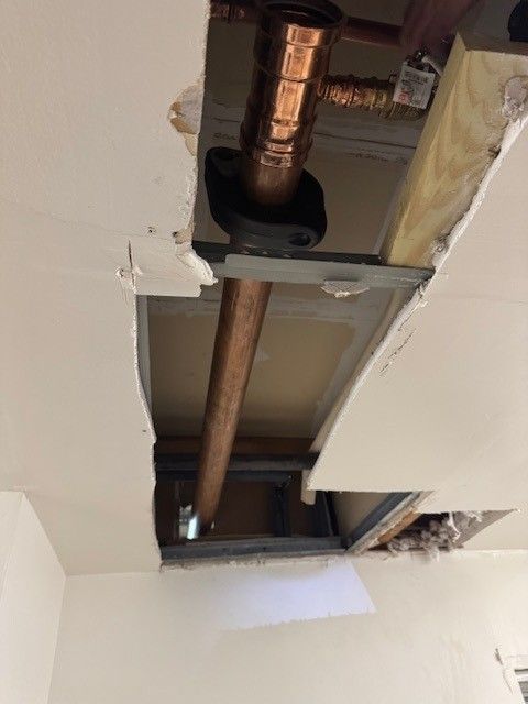 a copper, commercial 3 inch line going through an opening in the ceiling 