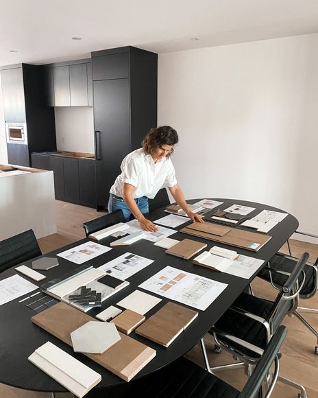 Woman standing at long table with several papers completing interior design in Toronto