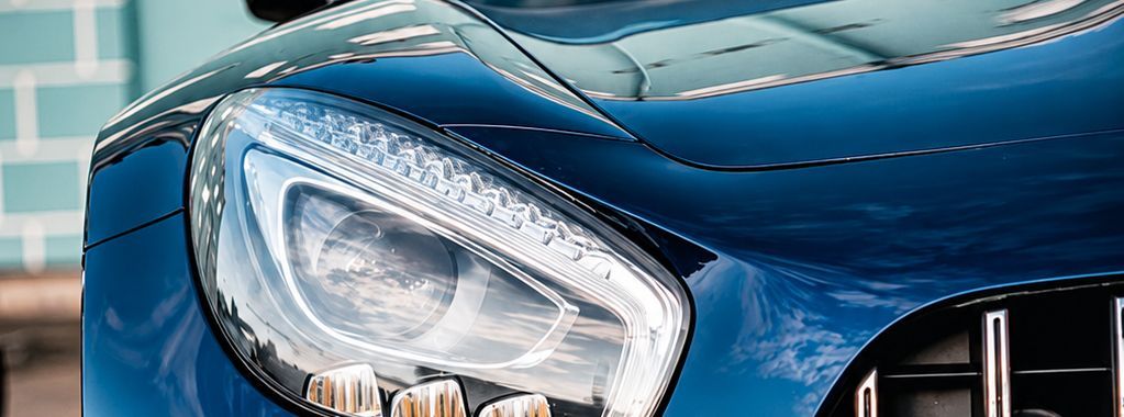 Close-up of a blue car’s headlight and front grille