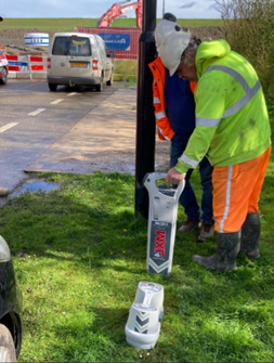 Een man in een groen jasje houdt een apparaat vast waarop 'rcr' staat