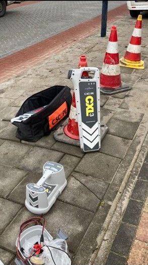 Er ligt een hoop gereedschap op de stoep, naast de verkeerskegels.