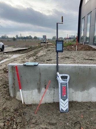 Een apparaat staat op de grond naast een betonnen muur.