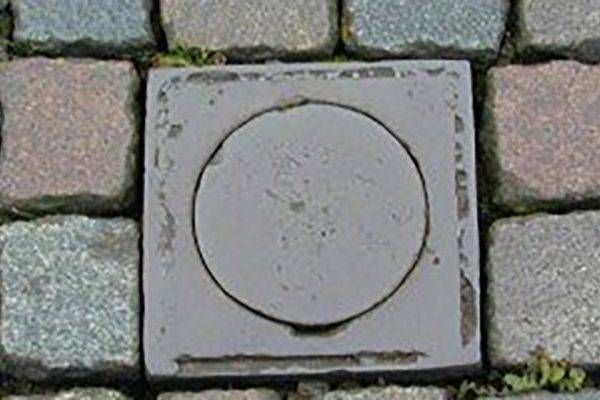 Een putdeksel op een geplaveide straat met een cirkel in het midden