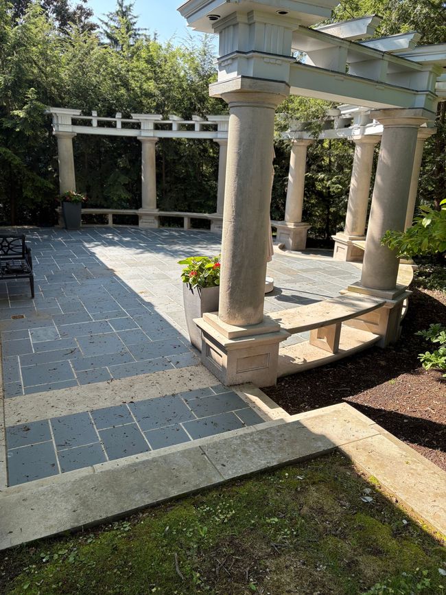 Stone pergola and columns over a paved courtyard