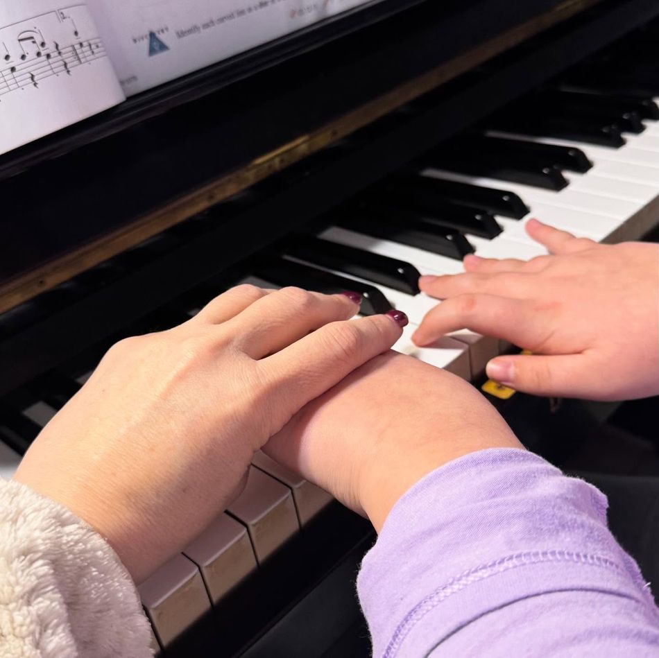 Hands on a piano keyboard with sheet music above.