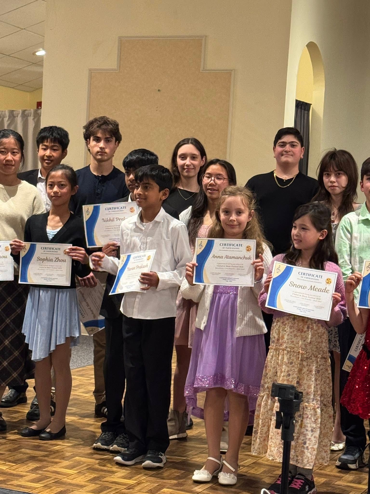 People holding certificates on a stage, posing for a group award photo