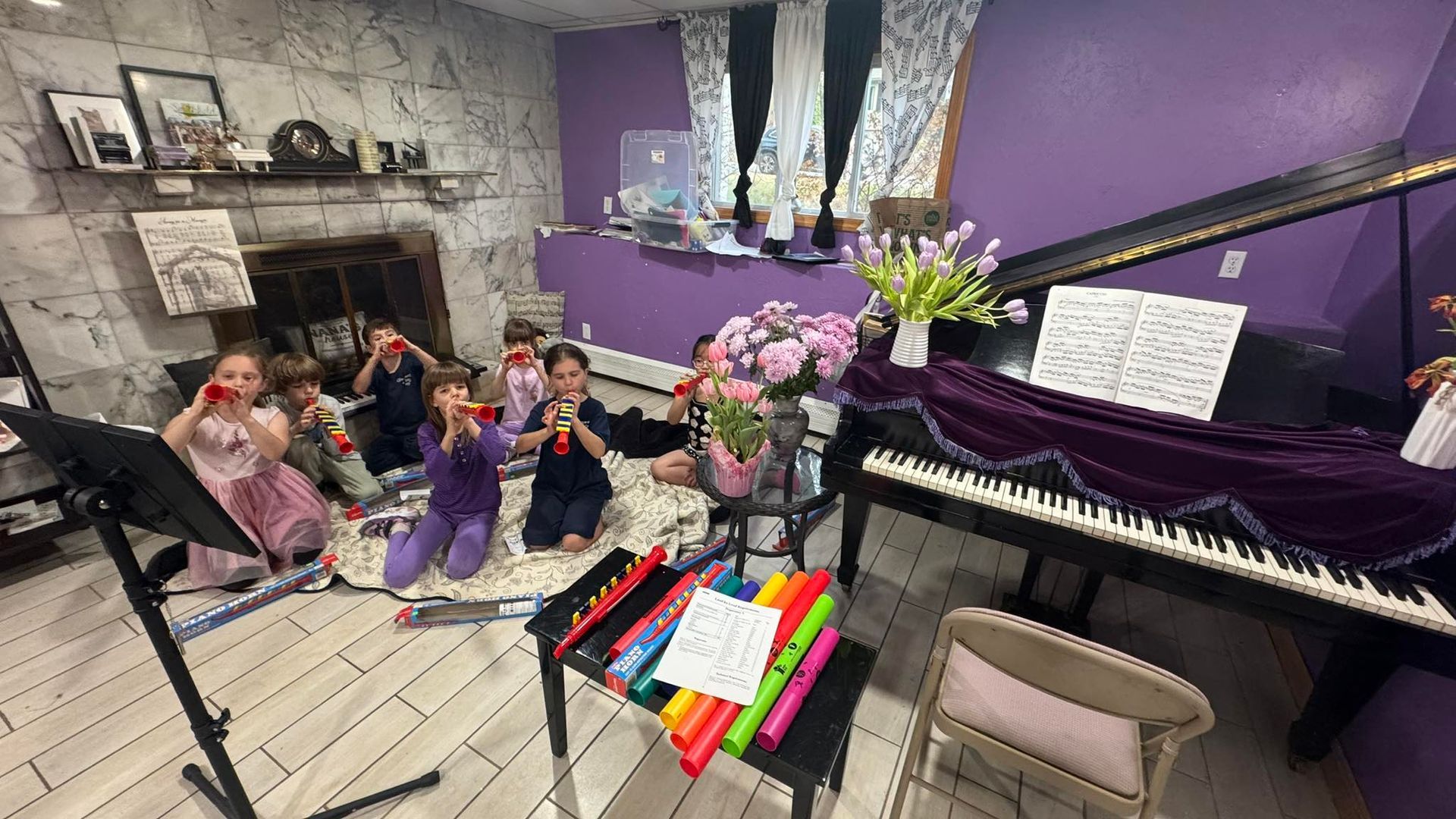 Purple music room with children sitting near a grand piano and a colorful xylophone on the floor