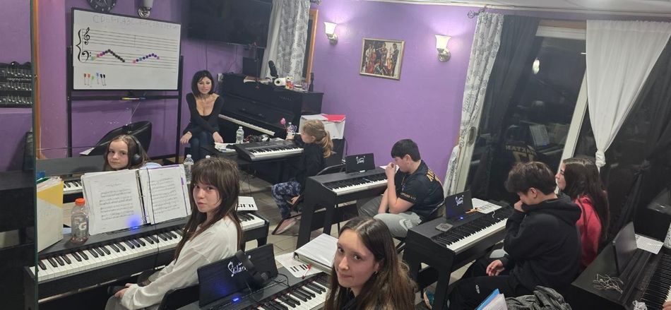 Group of students in a purple music classroom playing keyboards and listening to an instructor