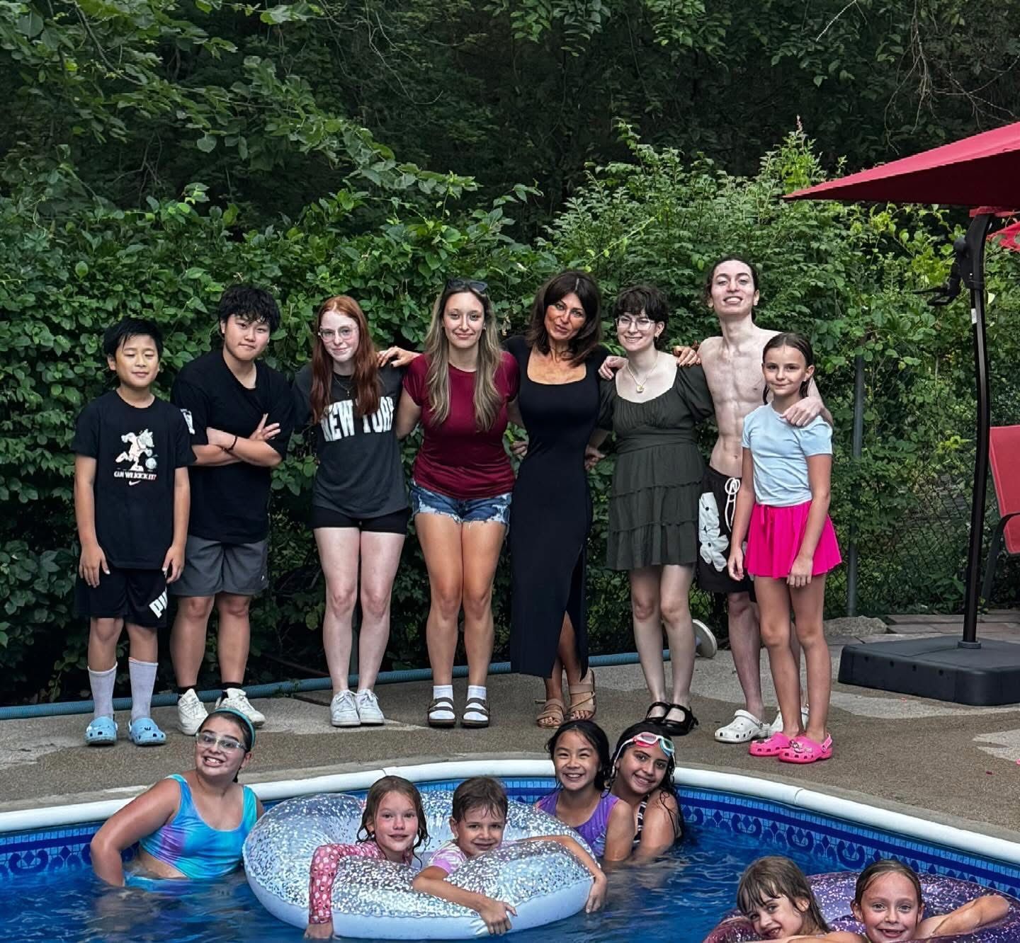 Group posing by a small pool outdoors, with several children and adults smiling near the water.