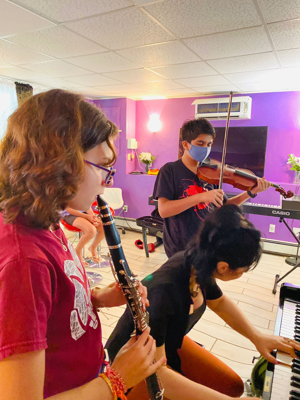 Students playing clarinet and violin in a purple music classroom