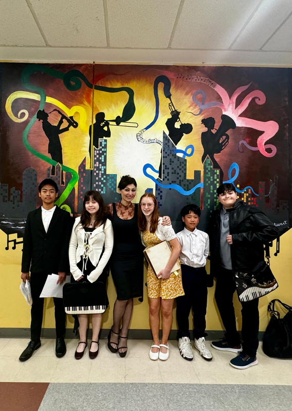 Seven people posing indoors before a colorful mural with musical silhouettes and paint-like swirls.