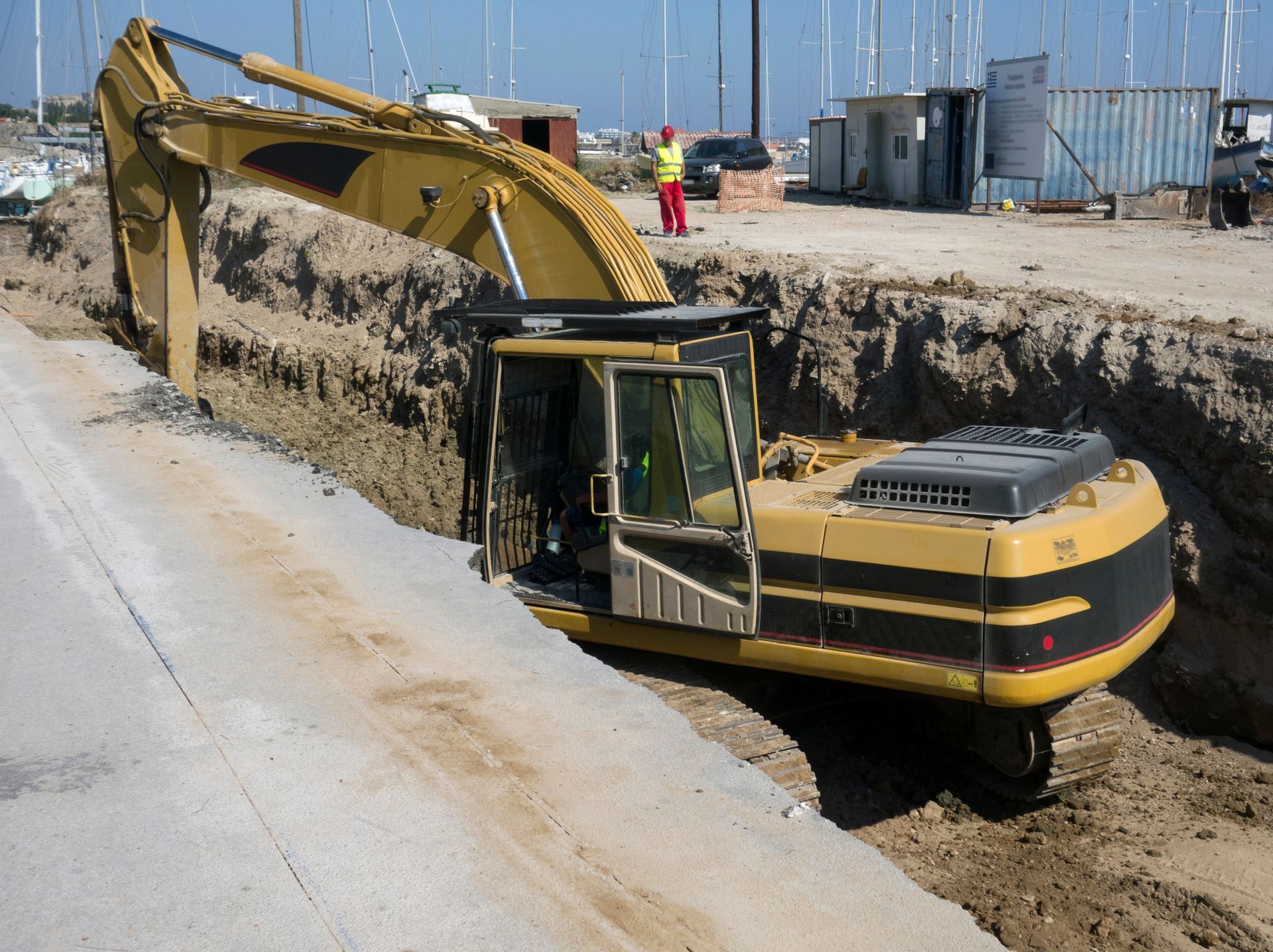 A yellow and black excavator is digging a hole in the ground. A yellow and black excavator is digging a hole in the ground.