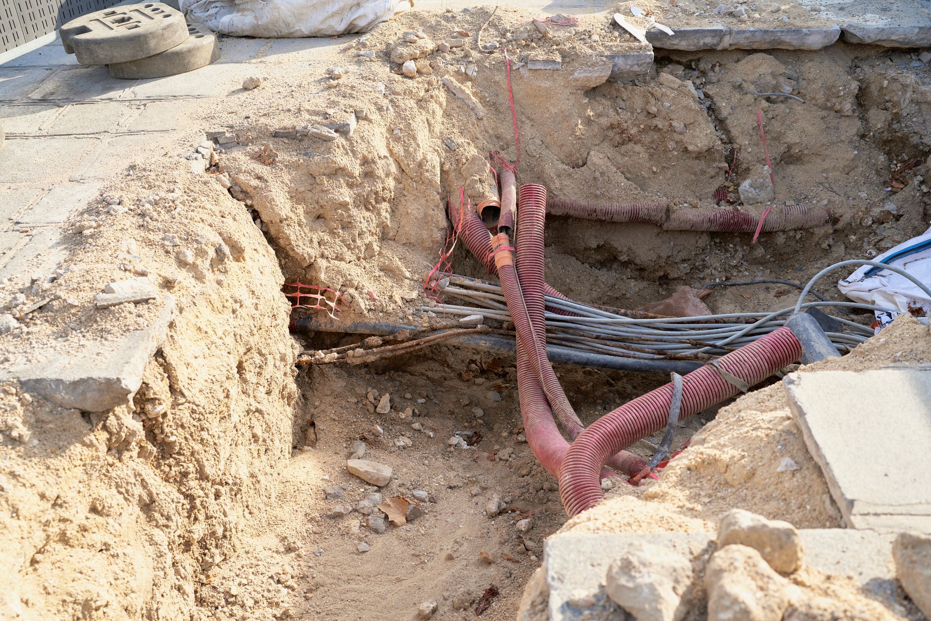 A hole in the ground with a bunch of wires coming out of it.