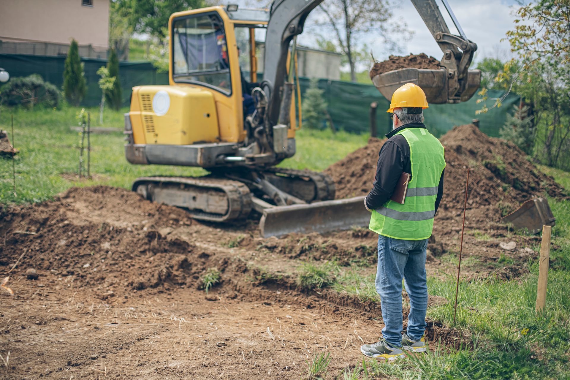 A construction worker is standing in front of a bulldozer at a construction site.