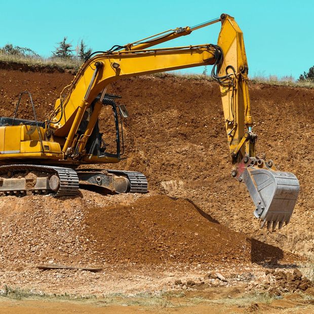 A yellow excavator is digging a hole in the dirt.