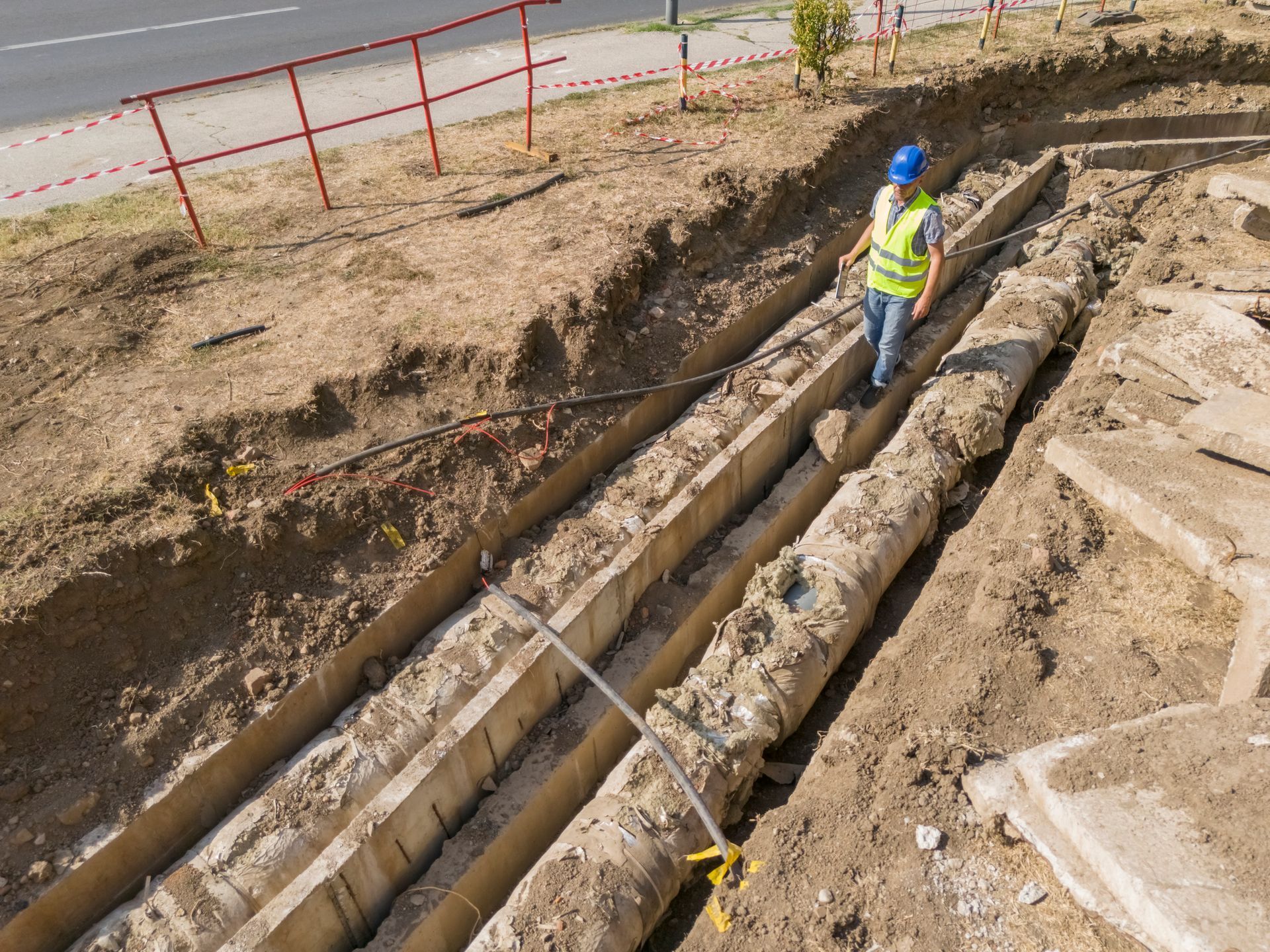 A construction worker is standing on a pile of dirt.