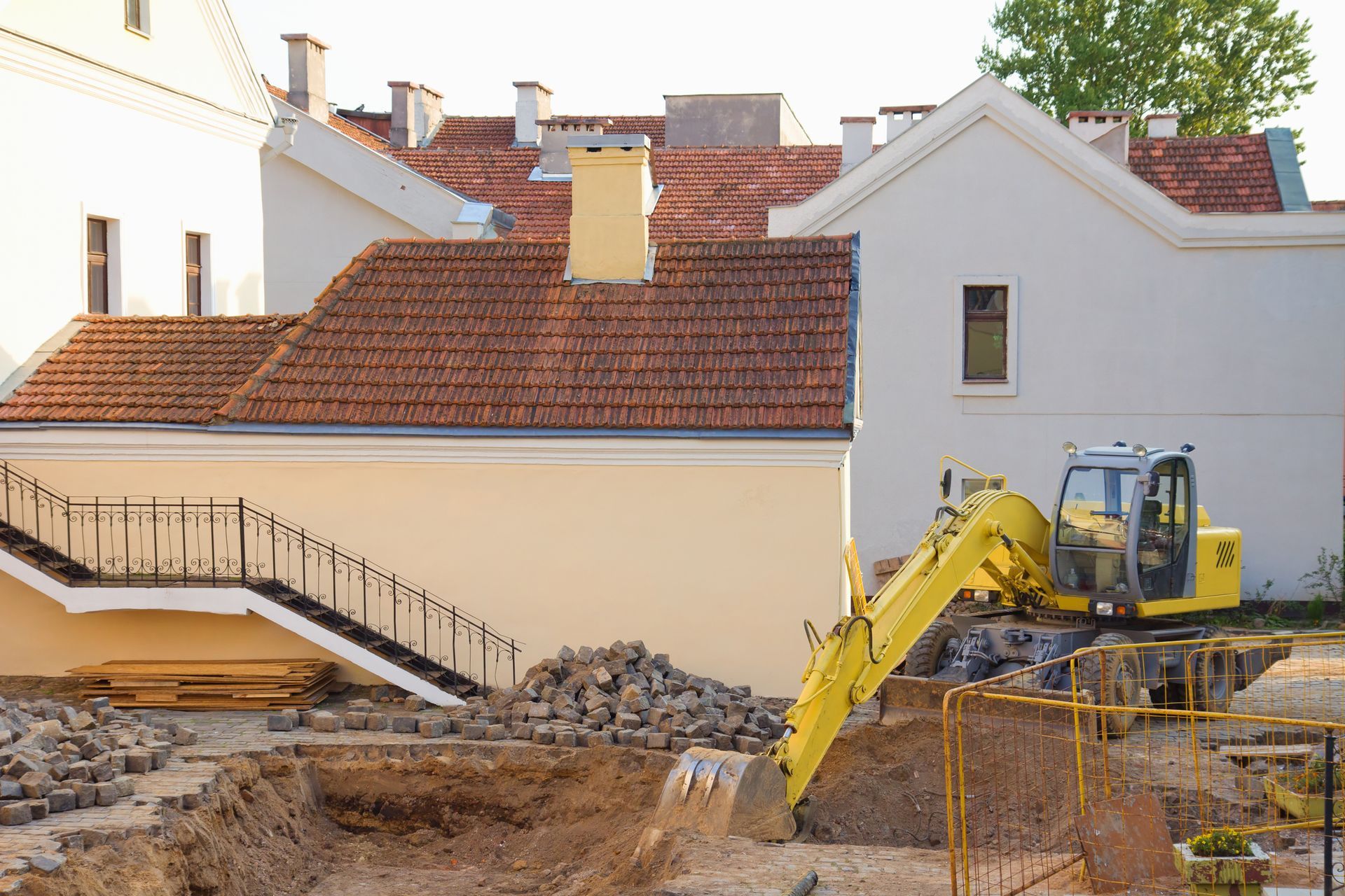 A yellow excavator is digging a hole in front of a building under construction.