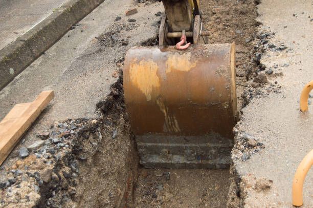 Excavation is underway for sewer line repair; utilities are exposed at the trench site.