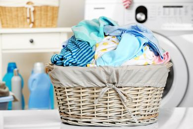 Overflowing laundry basket beside a washing machine in a bright laundry room Overflowing laundry basket beside a washing machine in a bright laundry room