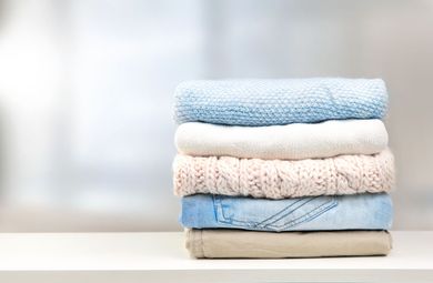 Stack of folded pastel towels on a white surface against a bright, blurred background Stack of folded pastel towels on a white surface against a bright, blurred background