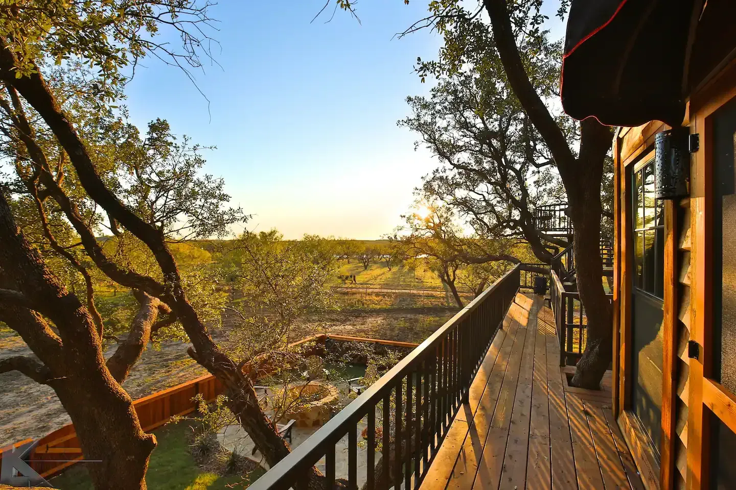 A wooden deck with a railing and trees in the background treehouse airbnb rental
