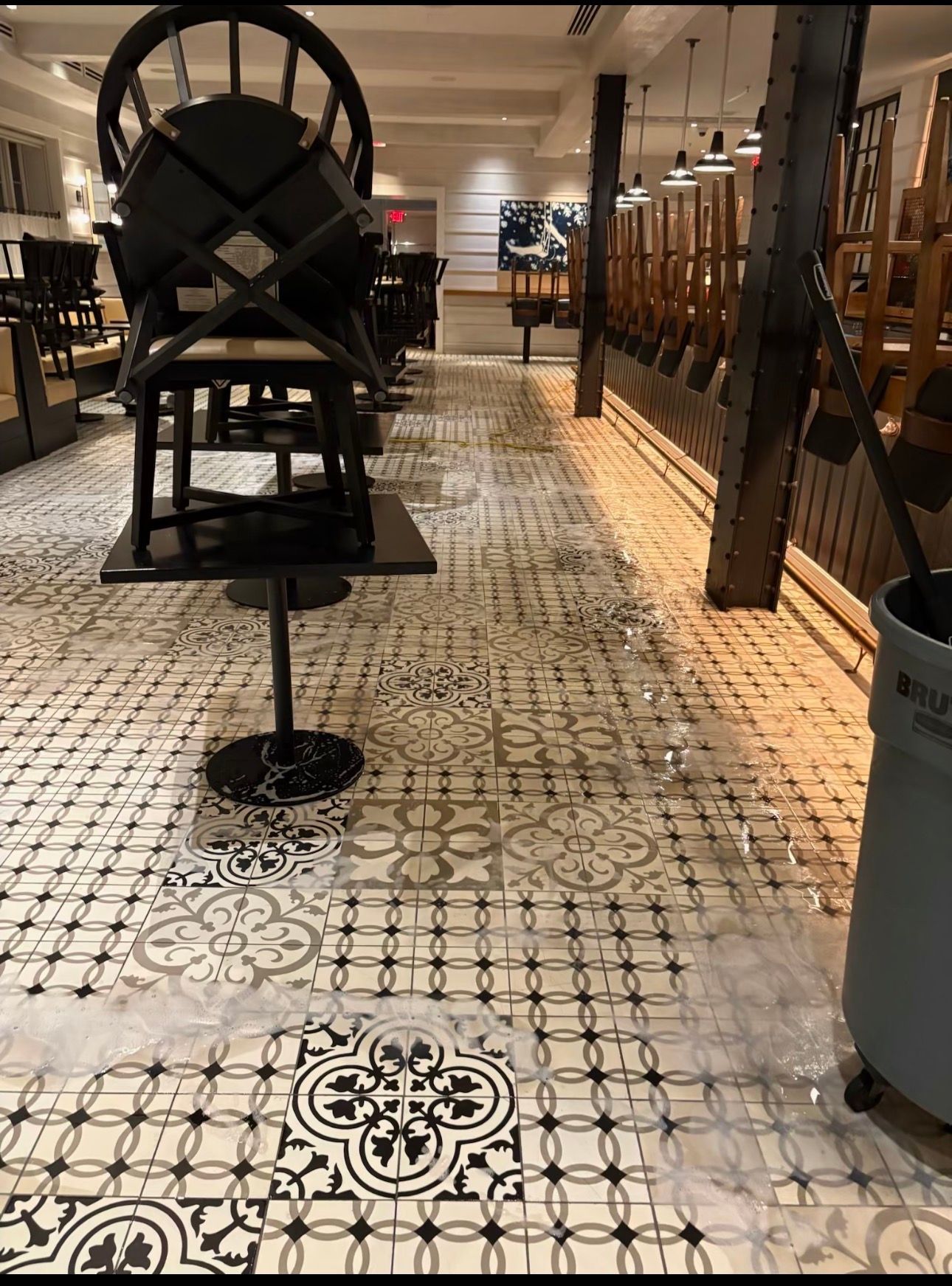 Tiled walkway in a vintage-style shop, with a large black machine display and glass cases on both sides.
