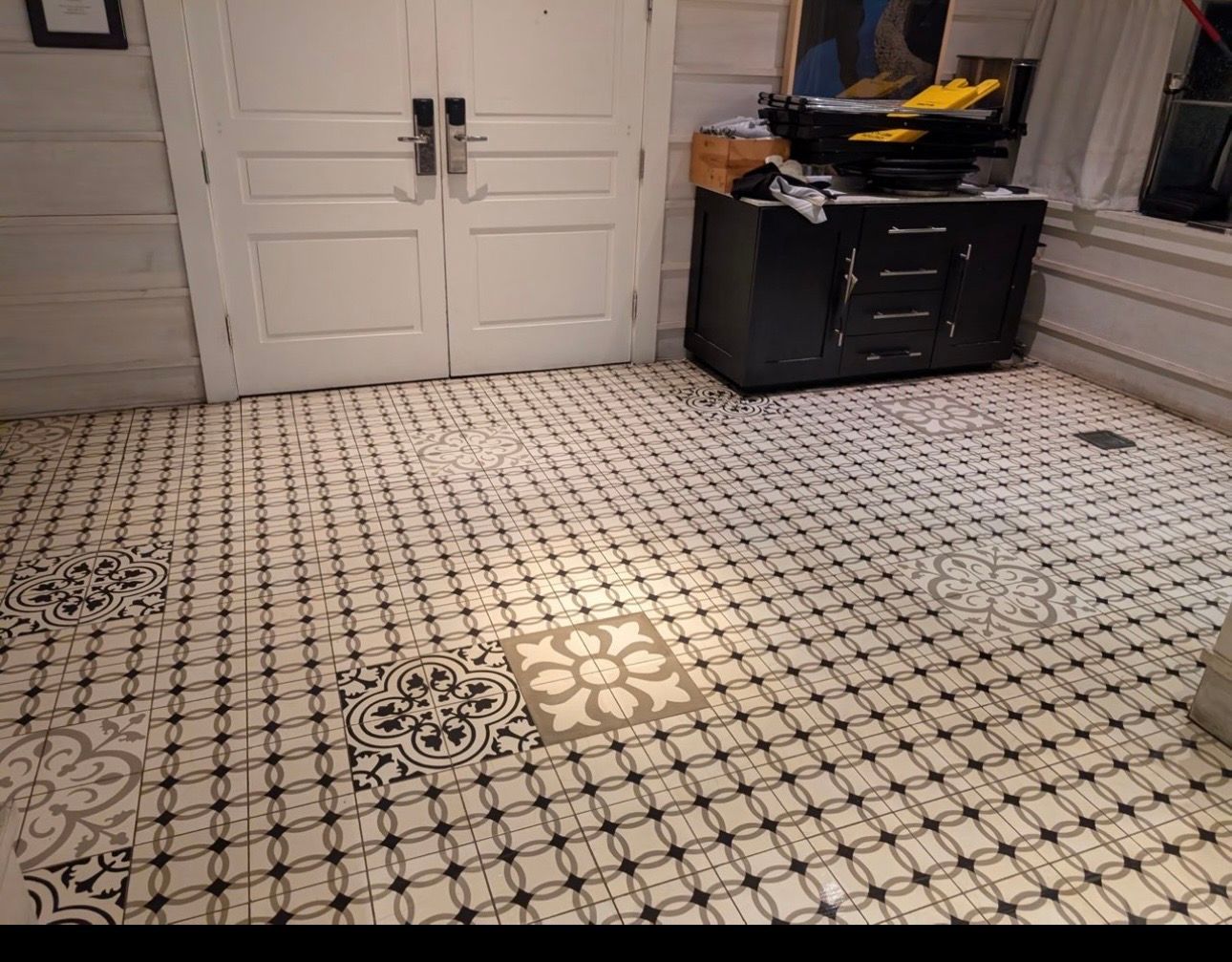 Tiled walkway in a vintage-style shop, with a large black machine display and glass cases on both sides.
