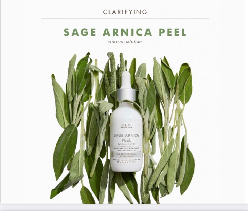 A bottle of Sage Arnica Peel sits centered atop a cluster of green sage leaves against a white background.