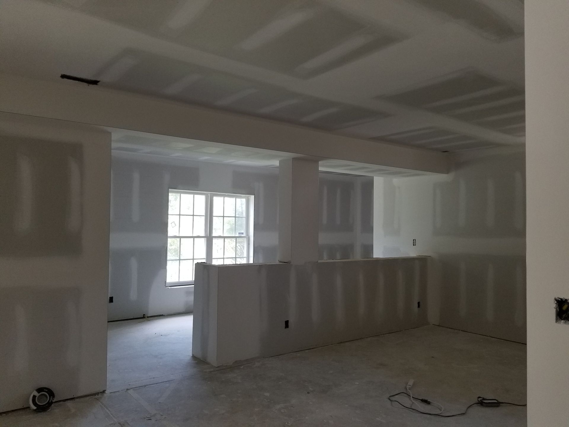 An empty room with drywall walls and a window
